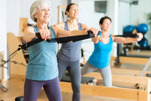 Toning Arms After 60: Empowering Womens Fitness Through Effective Weight Training 2 older woman doing weight training Hassocks and resistance in the gym to tone upper arms