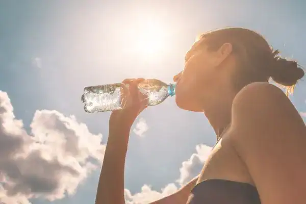 Hydration: The Secret Ingredient for a Toned Stomach and Enhanced Fitness 3 Image of woman drinking water to hydrate Hassocks after run.