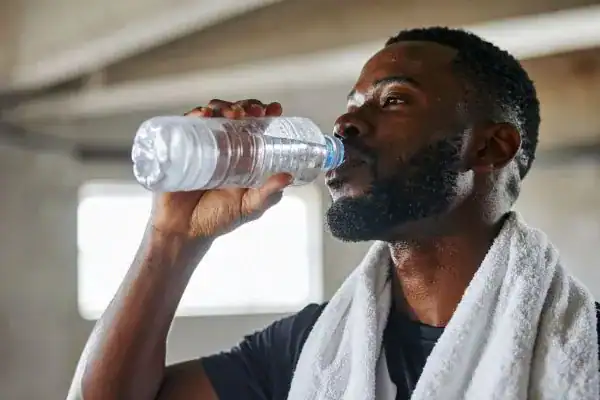 Image of man drinking water to improve hydration Hassocks after work out.